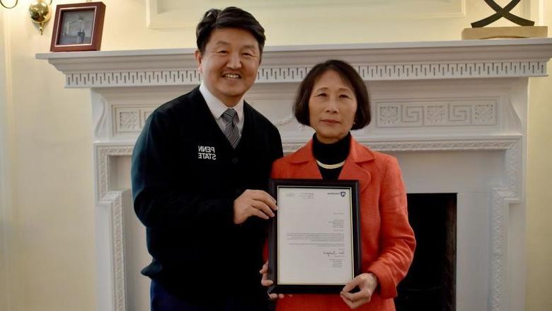 365英国上市校长兼首席学术官Jungwoo Ryoo, right, 向冯娟·沃纳赠送了一份装裱好的证明她为杰出教授的信件副本, 这所大学最高的教授荣誉